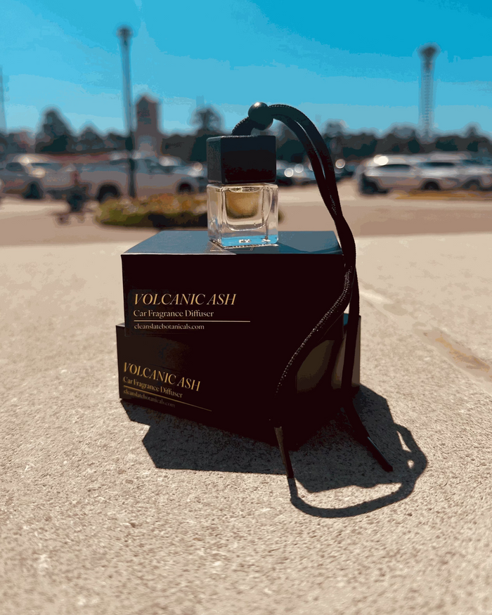 Volcanic Ash Car Diffuser in a clear glass bottle with a black cap and hanging cord, displayed with black packaging