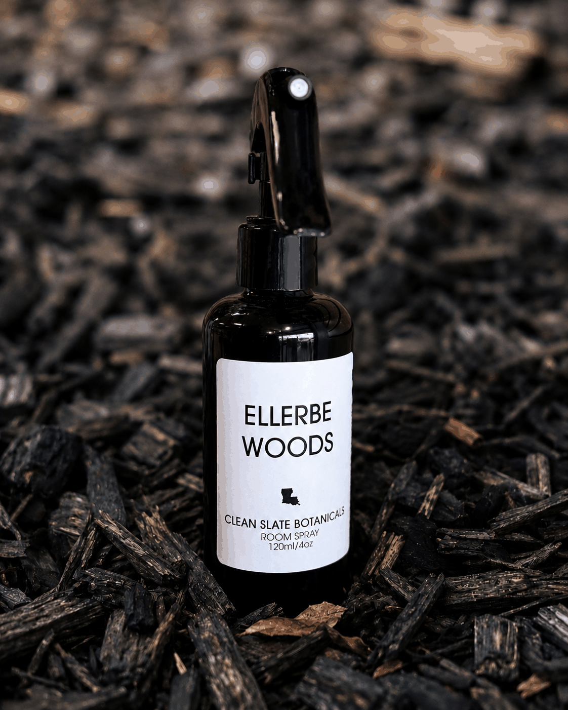Ellerbe Woods Room Spray in a black glass bottle with a white botanical label and black trigger sprayer