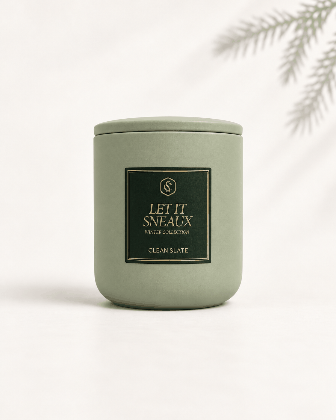 Let It Sneaux Candle in a matte sage-green ceramic vessel with a matching lid and black-and-gold label