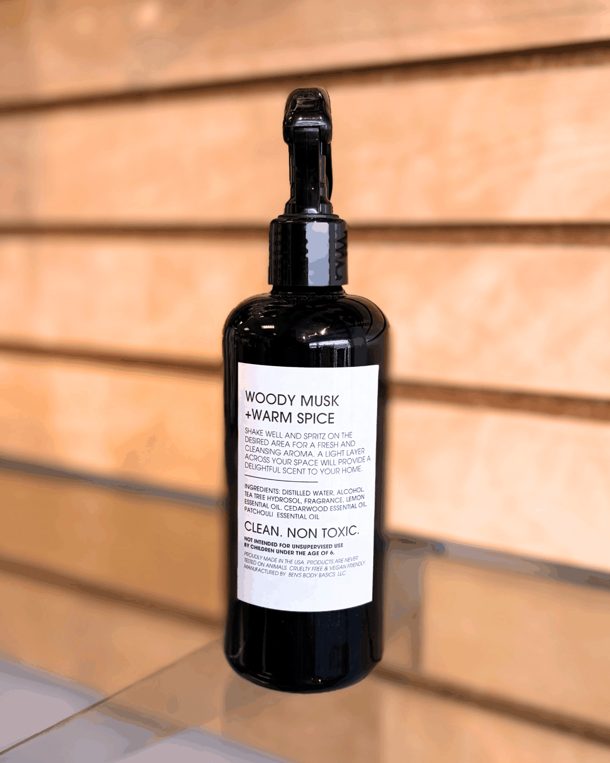 Palo Santo Room Spray in a sleek black plastic bottle with a fine-mist spray nozzle and white label detailing scent notes and usage